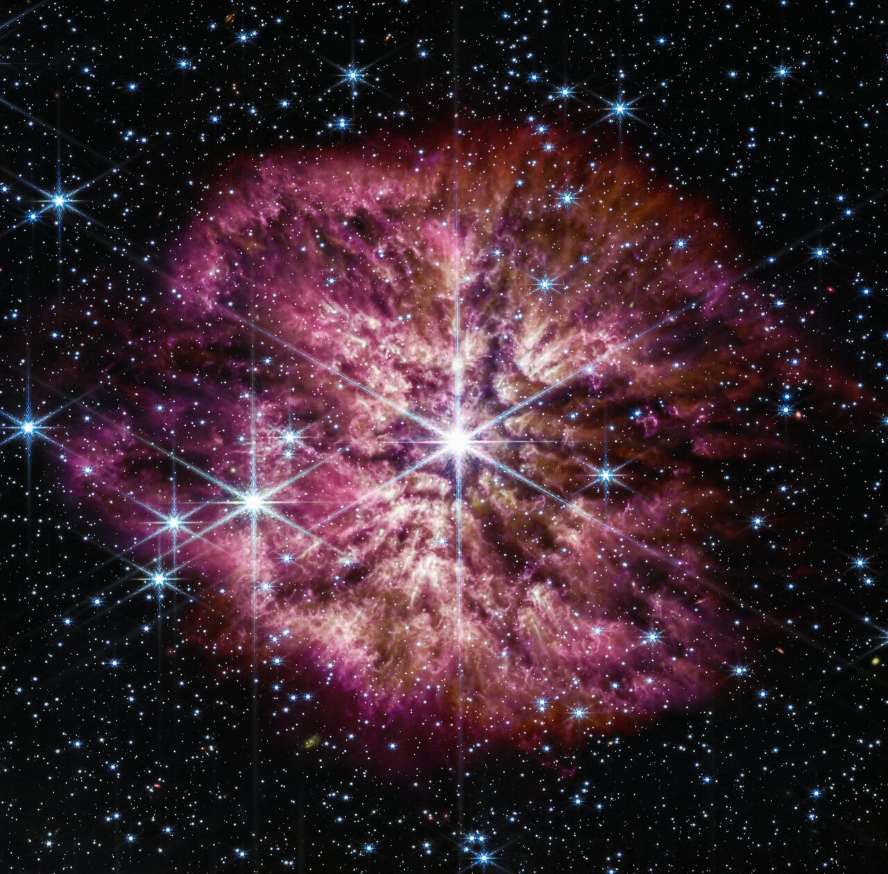 A large, bright star shines from the center with smaller stars scattered throughout the image. A clumpy cloud of material surrounds the central star, with more material above and below than on the sides, in some places allowing background stars to peek through. The cloud material is yellow closer to the star. Credit: NASA, ESA, CSA, STScI, Webb ERO Production Team